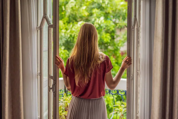 Una donna dai capelli rossi si trova su un balcone in stile heritage che si gode il suo caffè mattutino. Una donna in un hotel in Europa o in Asia mentre il turismo si riprende da una pandemia. Il turismo si è ripreso grazie a — Foto Stock