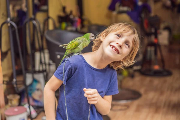 Niño jugando con su loro verde mascota — Foto de Stock