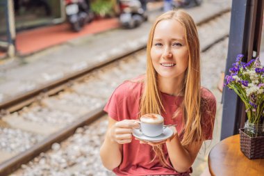 Genç bayan gezgin, Hanoi şehrinin yerleşim alanından geçen demiryolunun kenarında yumurtalı Vietnam kahvesi içer. Hanoi Tren Sokağı ünlü bir turizm merkezidir. Vietnam yeniden açılıyor