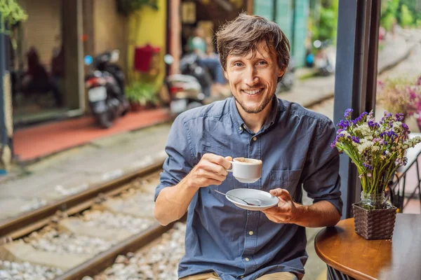 A fiatalember utazó vietnámi kávét iszik tojással a vasút mellett, ami Hanoi város lakónegyedén megy keresztül. Hanoi Train Street egy híres turisztikai célpont. Vietnam újra megnyitja kapuit — Stock Fotó