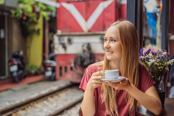 Молода жінка-мандрівниця п'є в'єтнамську каву з яйцем, що сидить біля залізничних шляхів, які проходять через житловий район міста Ханой. Ханой Трейн Стріт є відомим туристичним напрямком. В "єтнам знову відкривається — стокове фото