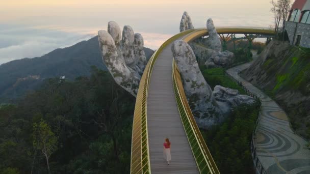 Slowmotion Plan aérien d'une jeune femme marchant sur le pont d'or dans la ville de Danang. Destination touristique au centre du Vietnam. Voyage au Vietnam concept — Video