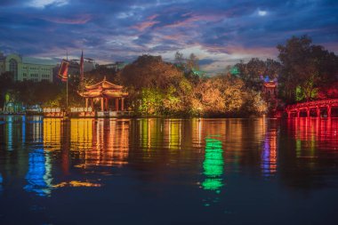 Gece vakti Hanoi Kızıl Köprüsü. Hoan Kiem Gölü üzerindeki ahşap kırmızı boyalı köprü kıyıyı ve Ngoc Son Tapınağı 'nın bulunduğu Jade Adası' nı birbirine bağlar.