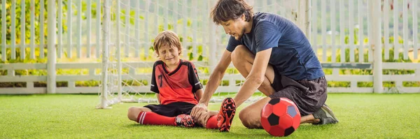 BANNER, LONG FORMAT Kis aranyos fiú piros labdarúgó egyenruhában és az edzője vagy apja focizik, focizik a pályán, a szabadban. Aktív gyermek sportolás gyerekekkel vagy apával, mosolygós boldog fiú — Stock Fotó