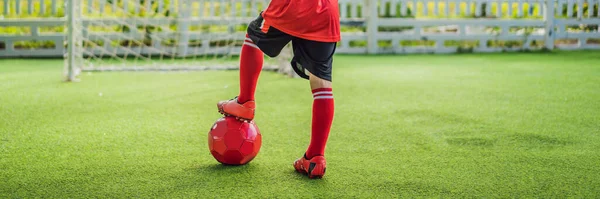 BANNER, LANG FORMAAT Kleine leuke jongen in rood voetbal uniform voetballen, voetbal op het veld, buiten. Actief kind maken sport met kinderen of vader, glimlachen gelukkige jongen plezier in de zomer — Stockfoto