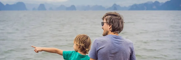 BANNER, LONG FORMAT Father and son travelers is traveling by boat in Halong Bay. Vietnam. Travel to Asia, happiness emotion, summer holiday concept. Traveling with children concept. After COVID 19