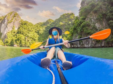 Anne, baba ve oğul gezginler COVID-19 Coronavirus sırasında tıbbi maske takıp Halong Körfezi 'ndeki bir kanoda kürek çekiyorlar. Vietnam. Asya 'ya seyahat, mutluluk duygusu, yaz tatili konsepti. Birlikte seyahat etmek.