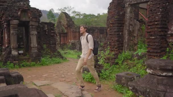 Un joven turista está caminando a través de ruinas en el Santuario de Mi Hijo, restos de una antigua civilización Cham en Vietnam.Destino turístico en la ciudad de Danang. Viajar a Vietnam concepto — Vídeos de Stock