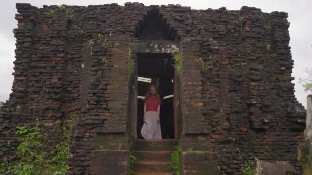 Una joven turista está caminando a través de ruinas en el Santuario de Mi Hijo, restos de una antigua civilización Cham en Vietnam.Destino turístico en la ciudad de Danang. Viajar a Vietnam concepto — Vídeos de Stock