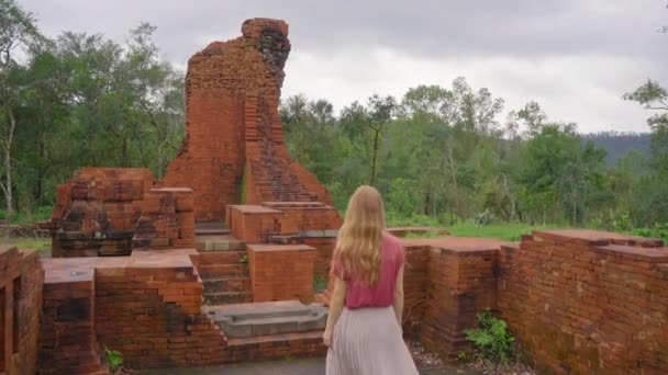 Een jonge vrouw toerist loopt door ruïnes in het My Son Sanctuary, overblijfselen van een oude Cham beschaving in Vietnam.Toeristische bestemming in de stad Danang. Reis naar Vietnam concept — Stockvideo