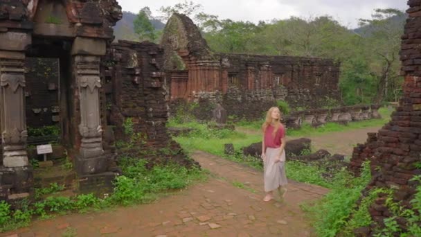 Μια νεαρή γυναίκα τουρίστας περπατά μέσα από ερείπια στο Ιερό του Υιού μου, ερείπια ενός αρχαίου πολιτισμού Cham στο Βιετνάμ. Τουριστικός προορισμός στην πόλη της Danang. Ταξίδι στο Βιετνάμ έννοια — Αρχείο Βίντεο
