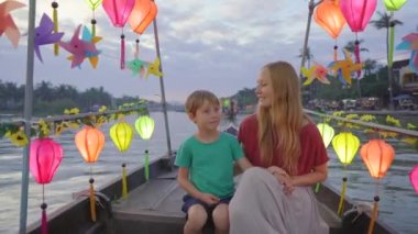 Genç bir kadın ve oğlu turistler Vietnam 'ın orta kesimindeki Hoi An antik bir kasabayı ziyaret ediyorlar. Parlak fenerlerle süslenmiş bir tekneye biniyorlar. Vietnam 'a seyahat