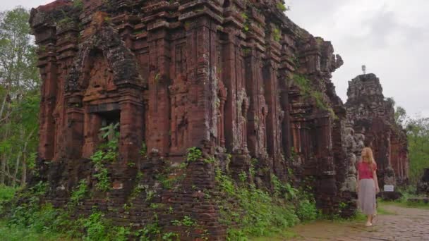 Een jonge vrouw toerist loopt door ruïnes in het My Son Sanctuary, overblijfselen van een oude Cham beschaving in Vietnam.Toeristische bestemming in de stad Danang. Reis naar Vietnam concept — Stockvideo