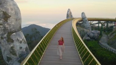 Danang şehrindeki Altın Köprü 'de yürüyen genç bir kadının yavaş çekim görüntüsü. Vietnam 'ın merkezinde bir turizm merkezi. Vietnam 'a seyahat