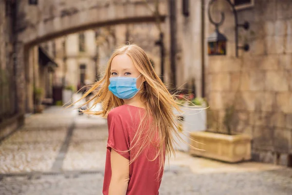 Mujer joven con una máscara médica durante COVID-19 coronavirus turista camina por la calle en una ciudad europea después del final de COVID-19 coronavirus. cuarentena — Foto de Stock