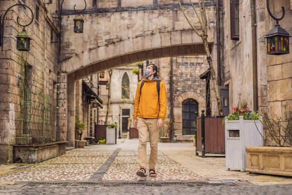 Ung man bär en medicinsk mask under COVID-19 coronavirus turist promenader ner på gatan i en europeisk stad efter slutet av COVID-19 coronavirus. karantän — Stockfoto