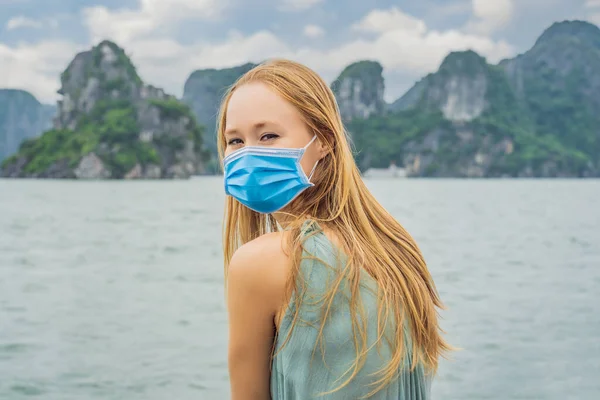Vonzó nő orvosi maszkot visel a COVID-19-es koronavírus idején, hajóval utazik Halong Bay-ben. Vietnámban. Utazás Ázsiába, boldogság érzelem, nyaralás koncepció. Festői tenger — Stock Fotó