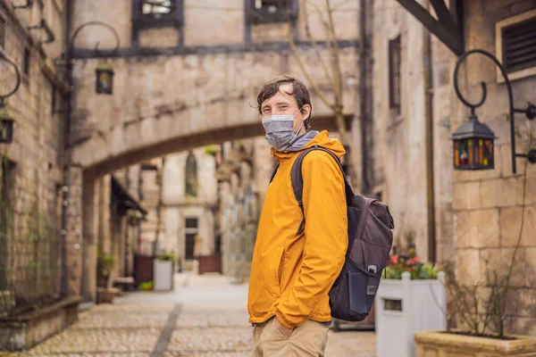 Young man wearing a medical mask during COVID-19 coronavirus tourist walks down the street in a European city after the end of COVID-19 coronavirus. quarantine — Stock Photo, Image