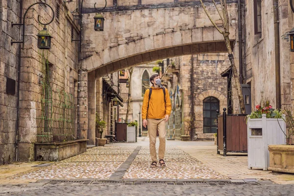 Ung man bär en medicinsk mask under COVID-19 coronavirus turist promenader ner på gatan i en europeisk stad efter slutet av COVID-19 coronavirus. karantän — Stockfoto