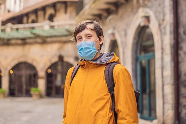 一名戴着医疗面具的年轻人在COVID-19科罗纳威斯之旅结束后，走在欧洲一个城市的大街上。检疫 — 图库照片
