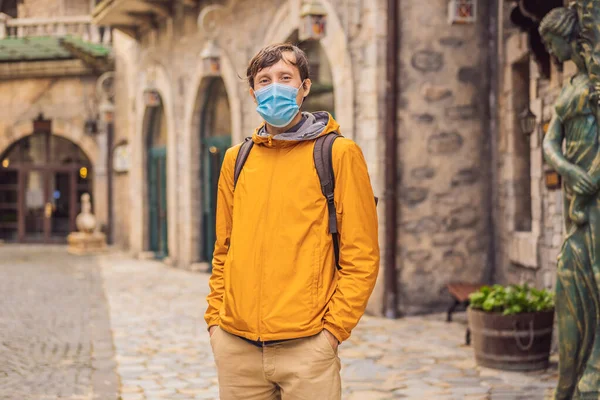 一名戴着医疗面具的年轻人在COVID-19科罗纳威斯之旅结束后，走在欧洲一个城市的大街上。检疫 — 图库照片