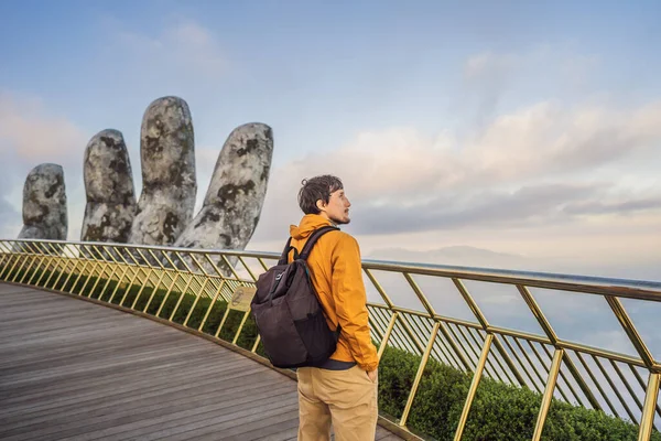 Молодой человек турист на знаменитой туристической достопримечательности - Золотой мост на вершине холмов Ба На, Вьетнам — стоковое фото