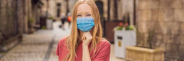 BANNER, LANG FORMAT Jonge vrouw met een medisch masker tijdens de COVID-19 coronavirus toeristische wandelingen door de straat in een Europese stad na het einde van COVID-19 coronavirus. quarantaine — Stockfoto