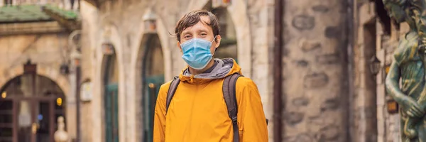 BANNER, DLOUHÝ FORMÁT Mladý muž v lékařské masce během COVID-19 koronavirus turistické procházky po ulici v evropském městě po konci COVID-19 coronavirus. karanténa — Stock fotografie