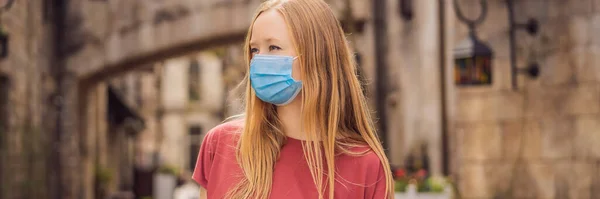 BANNER, LANG FORMAT Jonge vrouw met een medisch masker tijdens de COVID-19 coronavirus toeristische wandelingen door de straat in een Europese stad na het einde van COVID-19 coronavirus. quarantaine — Stockfoto