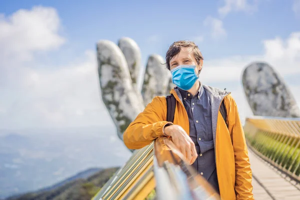 Young man tourist wearing a medical mask during COVID-19 coronavirus at Famous tourist attraction - Golden bridge at the top of the Ba Na Hills, Vietnam — Stock Photo, Image