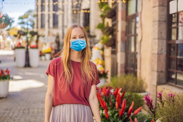 在欧洲一个城市，一名戴着医疗面罩的年轻女性游客在COVID-19的验尸报告结束后走在街上。检疫结束了 — 图库照片