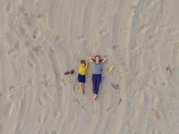Mutter und Sohn liegen bei Sonnenuntergang im Sand. Blick von der Drohne. Paradies, Reise, Urlaubskonzept — Stockfoto