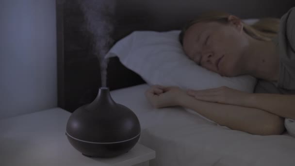 Ночью женщина поскальзывается в постели с ароматным диффузором, работающим на тумбочке. Глубокий и спокойный сон — стоковое видео