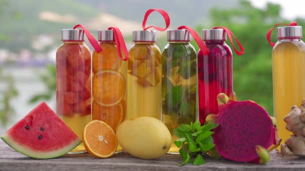 Um conjunto de garrafas de vidro coloridas com diferentes sabores de bebida de kombuchá, como melancia, laranja, manga, hortelã, fruta de dragão e gengibre. Bebidas saudáveis e naturais — Vídeo de Stock