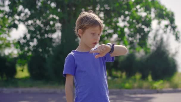 Ein kleiner Junge auf der Straße spricht mit seinen Eltern über seine Smartwatches. Sicherheitskonzept für Kinder — Stockvideo