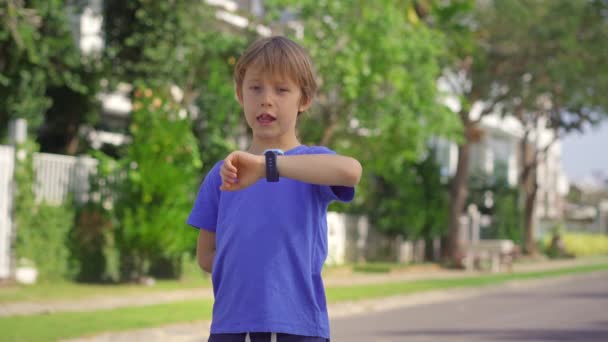 Ein kleiner Junge auf der Straße spricht mit seinen Eltern über seine Smartwatches. Sicherheitskonzept für Kinder — Stockvideo