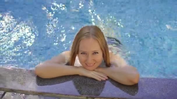 Una mujer joven se relaja y se lo pasa en grande en un balneario termal con piscinas de agua caliente. Ella está en la piscina de masaje — Vídeos de Stock