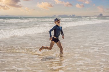 Çocuk deniz sörfünde koşuyor, mutlu bir çocukluk geçiriyor.