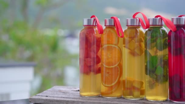 Μια σειρά από πολύχρωμα γυάλινα μπουκάλια με διαφορετικές γεύσεις του ποτού kombucha, όπως καρπούζι, πορτοκάλι, μάνγκο, μέντα, φρούτα δράκος. Υγιή και φυσικά ποτά — Αρχείο Βίντεο