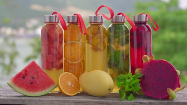 Een set kleurrijke glazen flessen met verschillende smaken kombucha drank, zoals watermeloen, sinaasappel, mango, munt, drakenfruit. Gezonde en natuurlijke dranken — Stockvideo