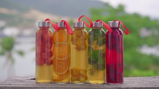 Um conjunto de garrafas de vidro coloridas com diferentes sabores de bebida de kombuchá, como melancia, laranja, manga, hortelã, fruta de dragão. Bebidas saudáveis e naturais — Vídeo de Stock