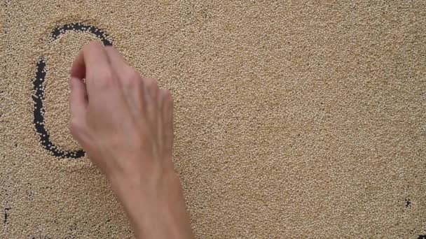 A man writes text on a black background using quinoa seeds. He writes text Quinoa — Stock Video