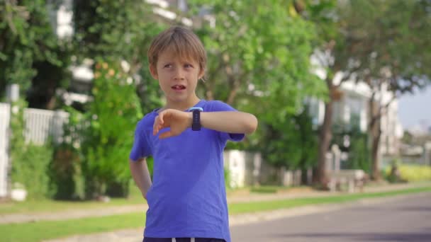 Ein kleiner Junge auf der Straße spricht mit seinen Eltern über seine Smartwatches. Sicherheitskonzept für Kinder — Stockvideo