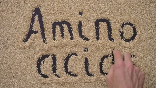 어떤 남자가 키 노아씨를 사용하여 검은 배경에 글을 쓴다. 그는 문자 AMINO ACIDS 를 쓴다 — 비디오