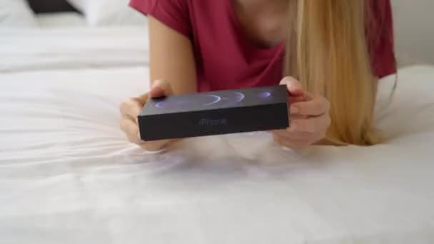 12.01.2021 - New York, USA: Young woman in her bedroom opens her new Iphone 12pro — Stock Video