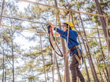 Kasklı mutlu bir çocuk, sağlıklı bir okul çocuğu yaz günü tırmanma parkında eğleniyor.