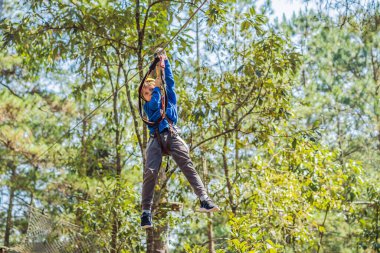 Kasklı mutlu bir çocuk, sağlıklı bir okul çocuğu yaz günü tırmanma parkında eğleniyor.