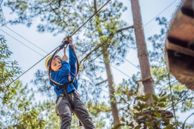 Kasklı mutlu bir çocuk, sağlıklı bir okul çocuğu yaz günü tırmanma parkında eğleniyor.
