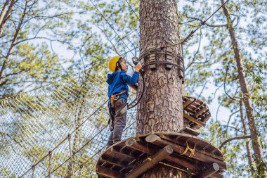 Kasklı mutlu bir çocuk, sağlıklı bir okul çocuğu yaz günü tırmanma parkında eğleniyor.