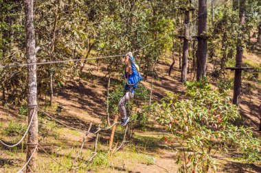 Kasklı mutlu bir çocuk, sağlıklı bir okul çocuğu yaz günü tırmanma parkında eğleniyor.